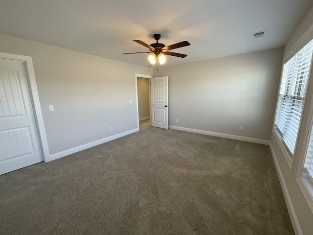 spare room with visible vents, dark carpet, baseboards, and ceiling fan