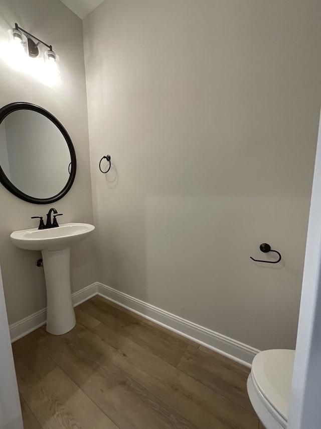 bathroom featuring toilet, baseboards, and wood finished floors