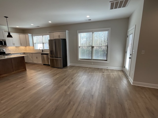 kitchen with stainless steel appliances, visible vents, white cabinets, hanging light fixtures, and light countertops