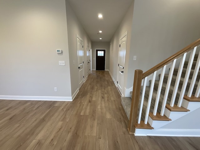 interior space with light wood-type flooring, baseboards, stairway, and recessed lighting