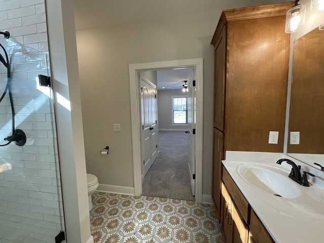 bathroom with toilet, a stall shower, baseboards, and vanity