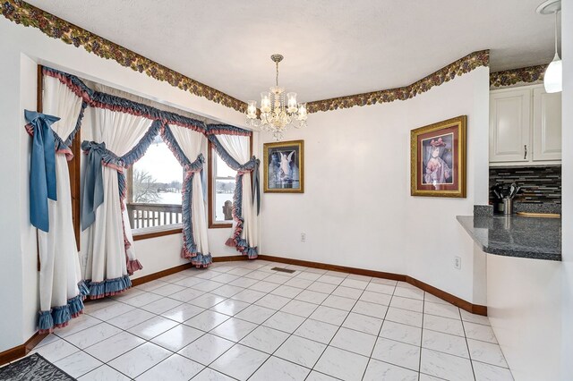 unfurnished dining area featuring visible vents, a textured ceiling, baseboards, and a notable chandelier