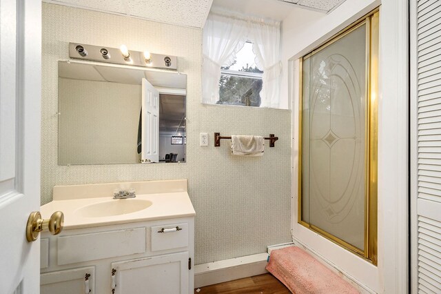 full bath with wallpapered walls, baseboards, a shower with door, vanity, and a closet