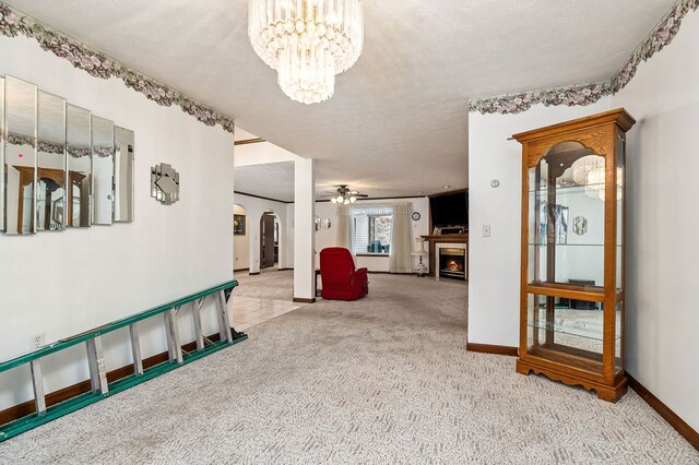 spare room featuring arched walkways, light colored carpet, a lit fireplace, and a textured ceiling