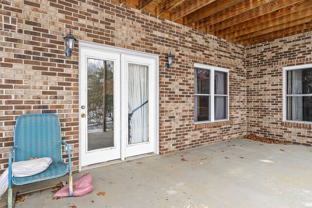 view of exterior entry featuring a patio area and brick siding