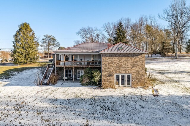 back of house featuring stairway, metal roof, a standing seam roof, a deck, and brick siding