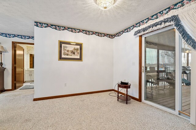 carpeted empty room featuring a textured ceiling and baseboards