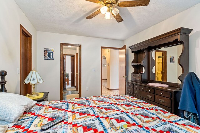 bedroom featuring a ceiling fan, a textured ceiling, ensuite bath, and light tile patterned floors