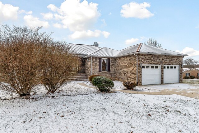 single story home with brick siding, metal roof, and an attached garage