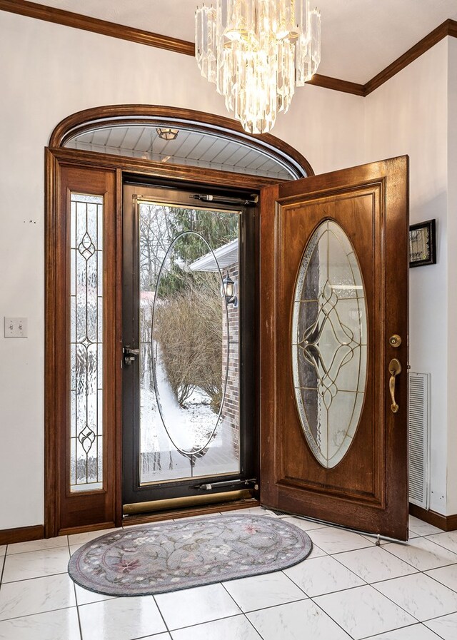 foyer featuring a notable chandelier, baseboards, visible vents, and crown molding