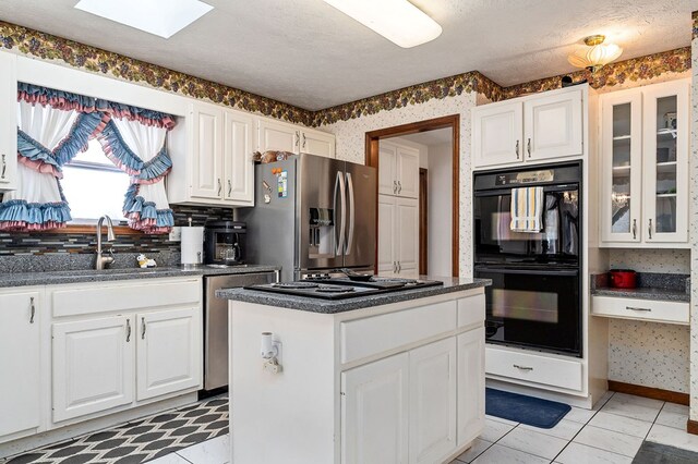 kitchen with white cabinetry, a kitchen island, black appliances, and wallpapered walls