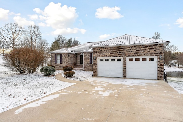 ranch-style home featuring concrete driveway, brick siding, metal roof, and an attached garage