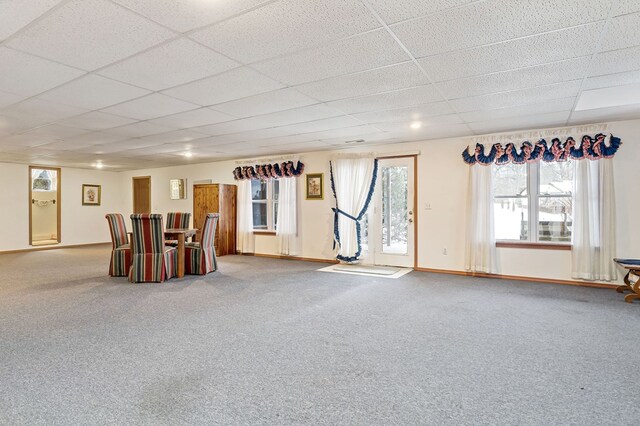 basement with carpet flooring, a paneled ceiling, and baseboards