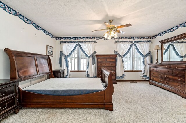 bedroom with light carpet, multiple windows, a textured ceiling, and a ceiling fan