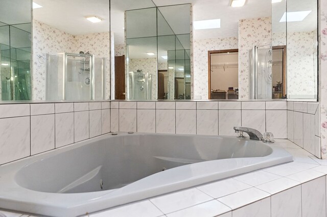 bathroom with a garden tub, a spacious closet, a shower stall, and wallpapered walls