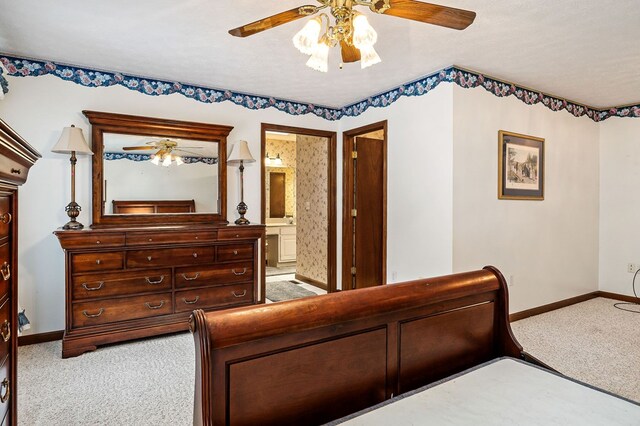 bedroom featuring light carpet, ceiling fan, ensuite bathroom, and baseboards