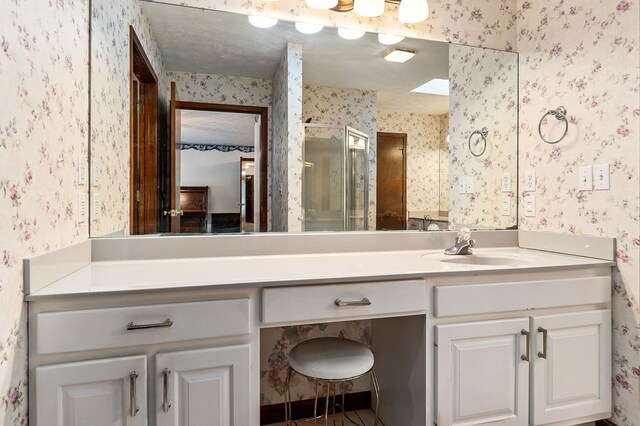 full bathroom with wallpapered walls, vanity, a textured ceiling, and a stall shower