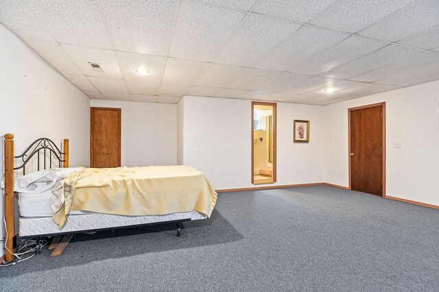 carpeted bedroom featuring visible vents, a drop ceiling, and baseboards