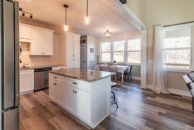 kitchen with a kitchen island, backsplash, dark wood-style floors, white cabinetry, and stainless steel appliances