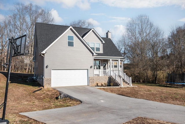 traditional home with a porch, an attached garage, a chimney, concrete driveway, and a trampoline