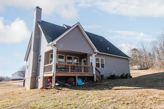 back of house with a deck, a yard, roof with shingles, and a chimney