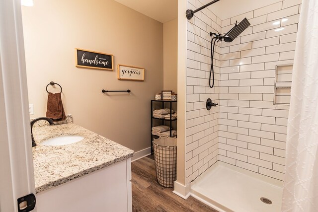 bathroom featuring baseboards, wood finished floors, a stall shower, and vanity