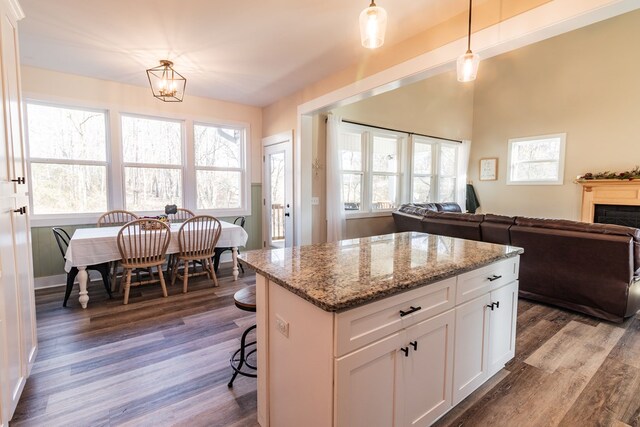 kitchen featuring light stone counters, dark wood finished floors, hanging light fixtures, and white cabinetry