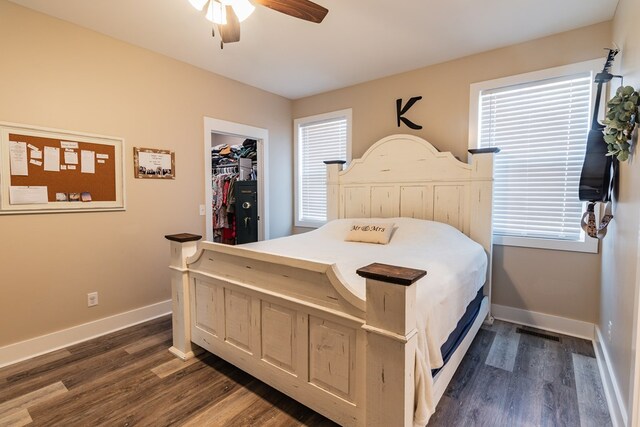 bedroom featuring a spacious closet, ceiling fan, baseboards, and dark wood-style flooring