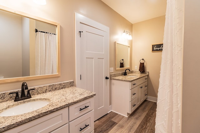 bathroom with a sink, baseboards, two vanities, and wood finished floors