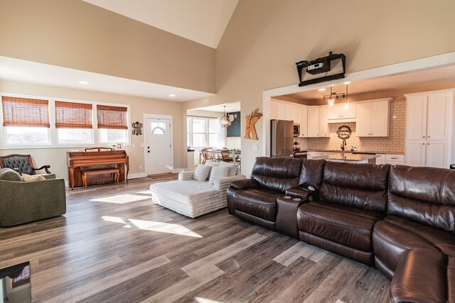 living area featuring an inviting chandelier, dark wood-type flooring, recessed lighting, and high vaulted ceiling