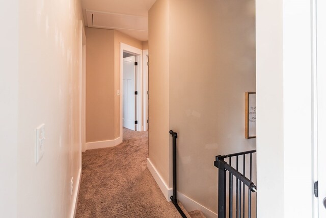 hallway featuring an upstairs landing, baseboards, and carpet