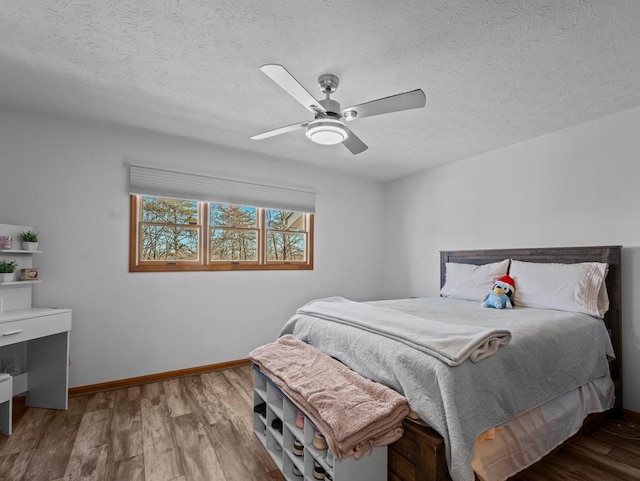 bedroom featuring a textured ceiling, baseboards, and wood finished floors