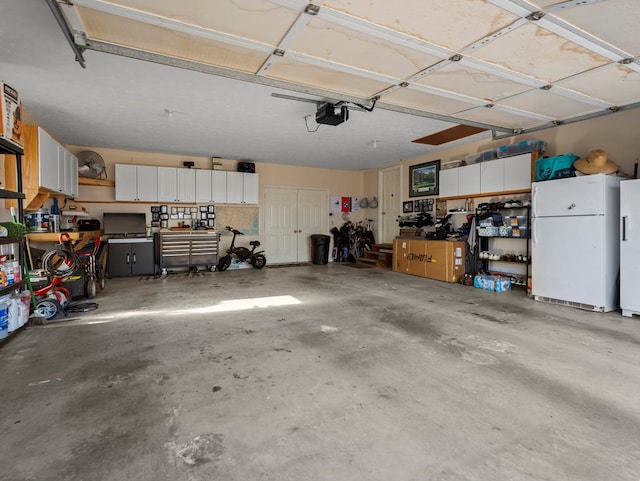 garage featuring a workshop area, freestanding refrigerator, and a garage door opener