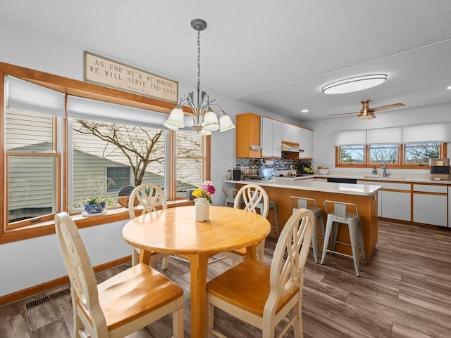 dining space with recessed lighting, ceiling fan with notable chandelier, wood finished floors, visible vents, and baseboards