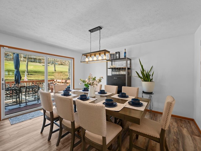 dining area featuring a textured ceiling, wood finished floors, and baseboards