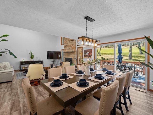 dining space with a chandelier, a textured ceiling, and light wood-style flooring