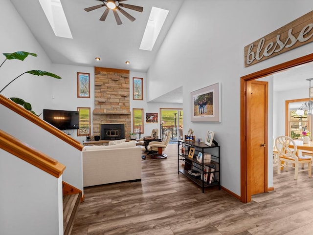 living area with a skylight, high vaulted ceiling, and wood finished floors