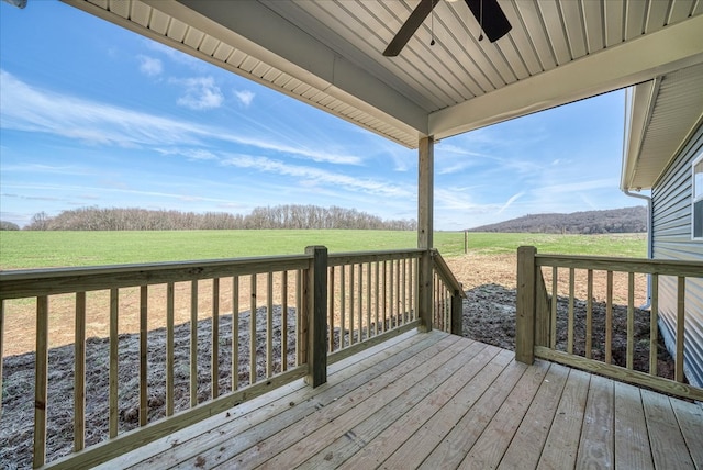 wooden terrace featuring a lawn, a ceiling fan, and a rural view