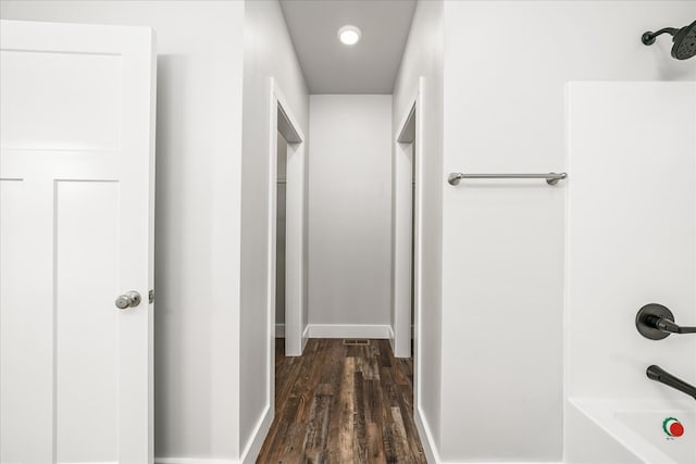 corridor with dark wood-style floors and baseboards