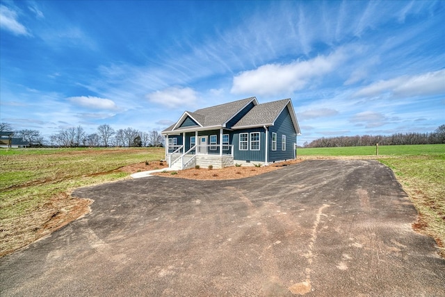 view of front of home with covered porch, dirt driveway, crawl space, and a front yard