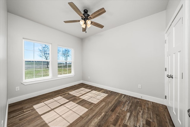 unfurnished room with ceiling fan, dark wood finished floors, and baseboards