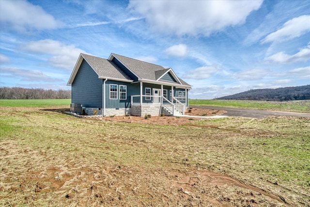 view of front of house with crawl space, covered porch, a shingled roof, and a front lawn