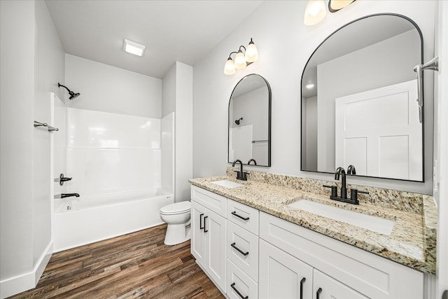 bathroom with toilet, shower / bathtub combination, a sink, and wood finished floors