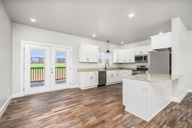 kitchen featuring white cabinets, dark wood-style floors, appliances with stainless steel finishes, pendant lighting, and a sink