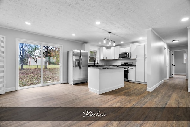 kitchen featuring a kitchen island, white cabinetry, hanging light fixtures, appliances with stainless steel finishes, and dark countertops