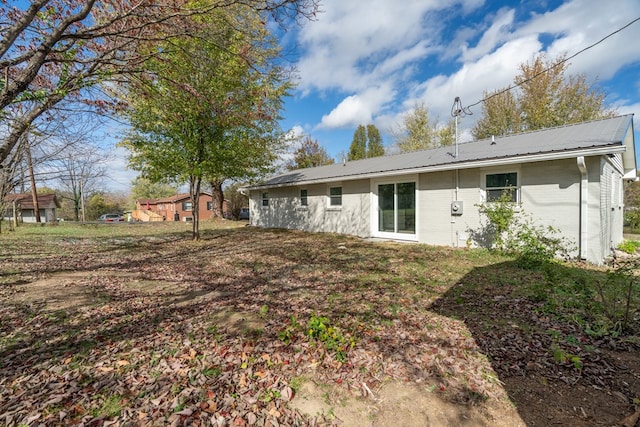 back of property featuring metal roof and brick siding