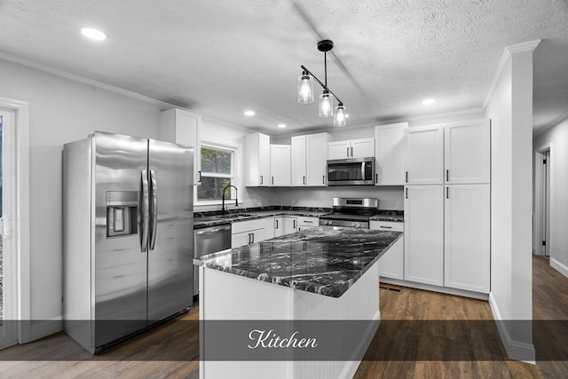 kitchen featuring stainless steel appliances, white cabinetry, a kitchen island, and crown molding