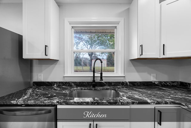 kitchen with stainless steel dishwasher, white cabinetry, dark stone counters, and a sink