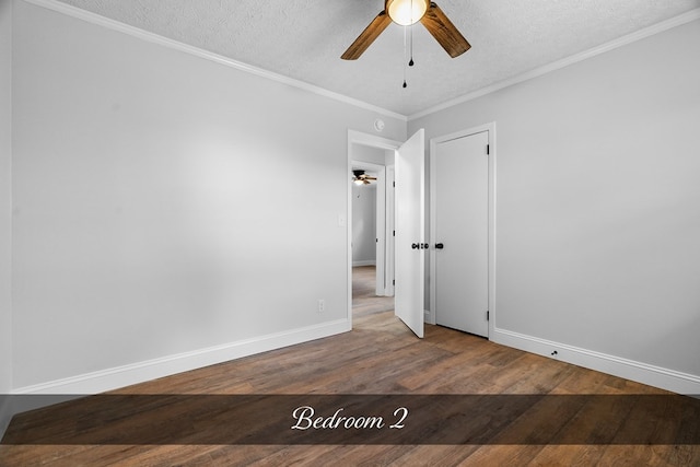 spare room with ceiling fan, a textured ceiling, ornamental molding, and wood finished floors