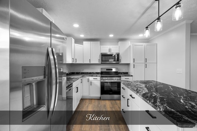 kitchen with hanging light fixtures, white cabinets, stainless steel appliances, and dark stone countertops